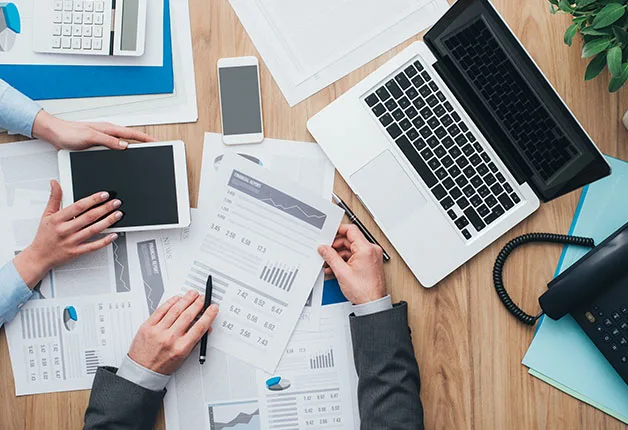Mesa de trabajo con informes financieros, portátil y tableta